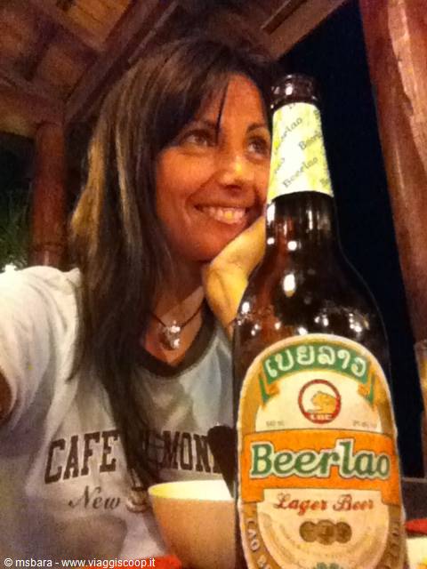 Smile next to a Beerlao bottle in a wooden restaurant