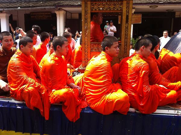 Monks in orange robes seated on a decorated float during a procession