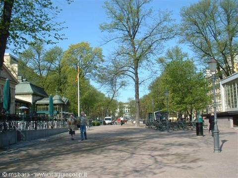 Tree-lined Esplanadi park in Helsinki with strollers and a wooden kiosk