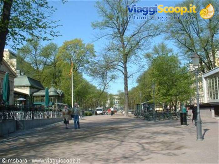 Tree-lined Esplanadi park in Helsinki with strollers and a wooden kiosk