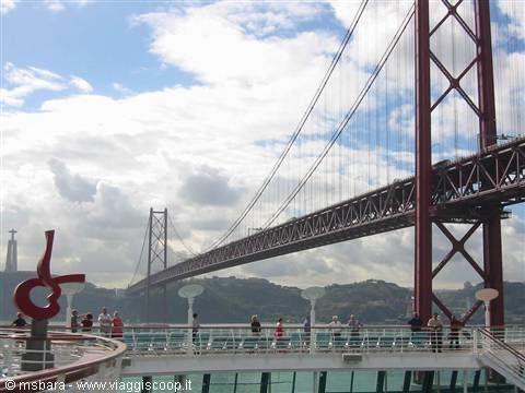 Tourists on ship deck beneath the 25 de Abril Bridge in Lisbon