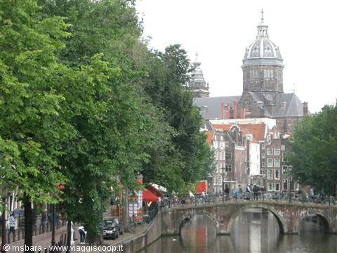 Amsterdam canal with brick bridge and dome of Saint Nicholas basilica