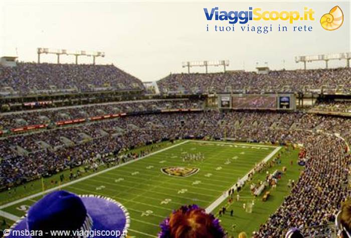 Football stadium packed with fans, green lit field with game underway