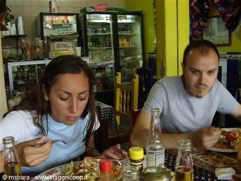 Couple eating tacos in a small eatery with drink fridge and condiments
