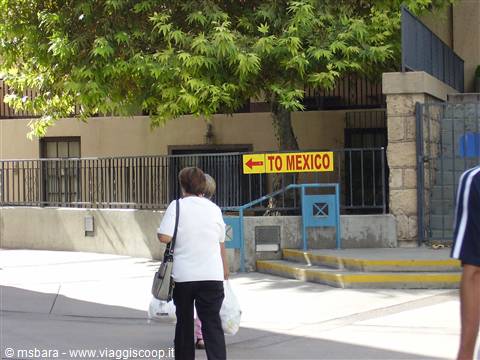 Woman with bag walks toward the yellow To Mexico arrow sign