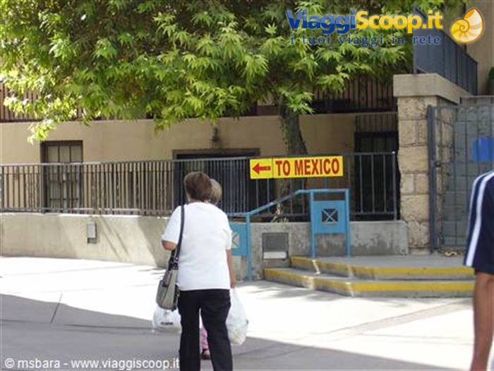 Woman with bag walks toward the yellow To Mexico arrow sign