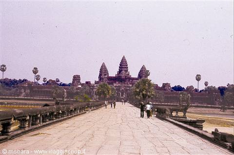 Tourists walk on the stone causeway toward Angkor Wat towers