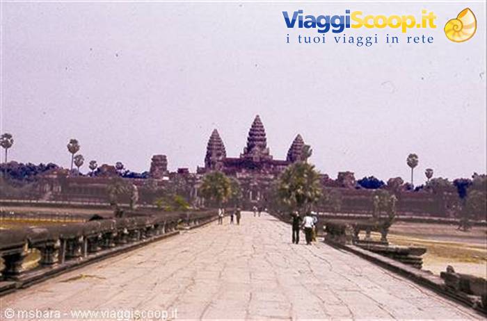 Tourists walk on the stone causeway toward Angkor Wat towers