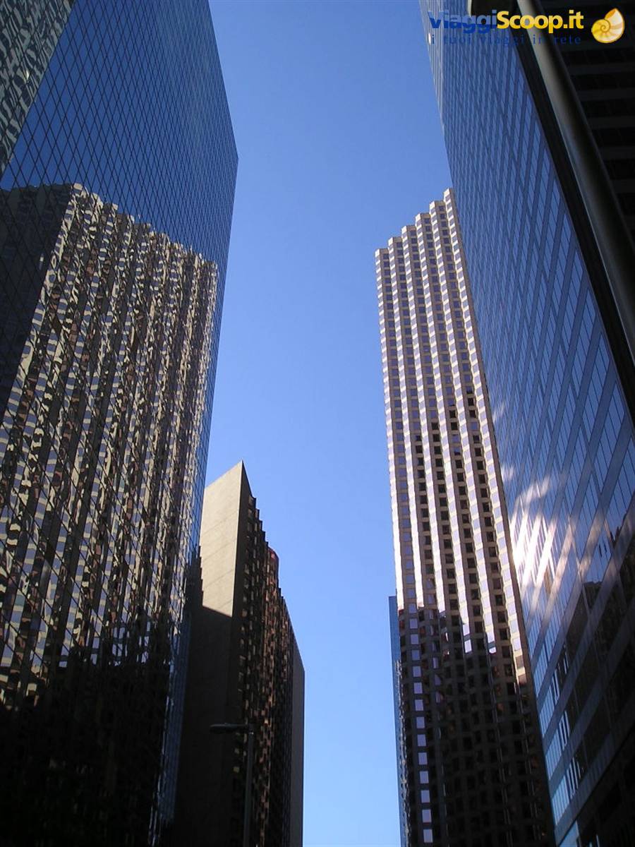 Glass skyscrapers with reflective facades against blue sky, seen from below