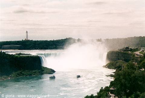Niagara Falls with white mist, tour boats on the green river