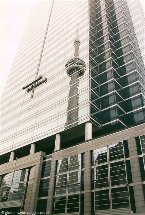 The CN Tower reflected in the glass facade of a Toronto skyscraper