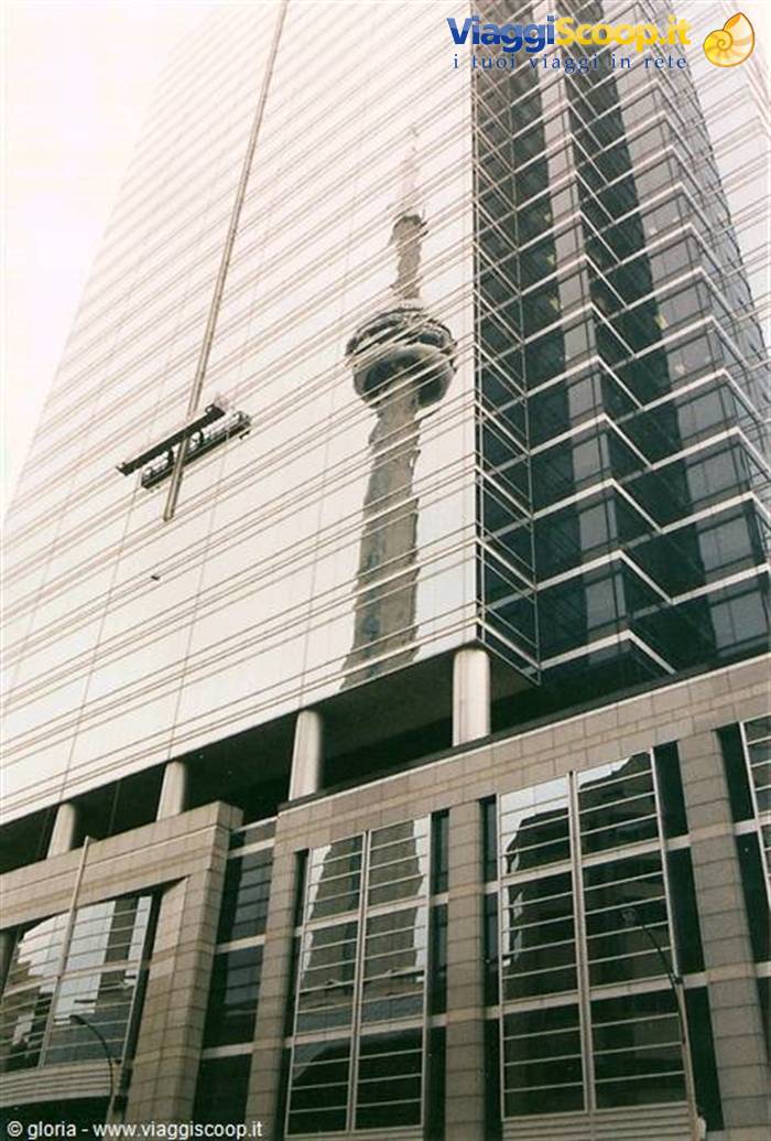 The CN Tower reflected in the glass facade of a Toronto skyscraper