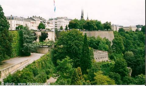 Luxembourg city fortifications covered in greenery, cathedral spires and flag