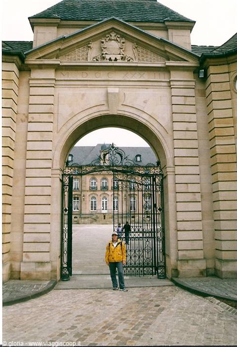 Tourist in yellow jacket under a stone archway with wrought iron gate