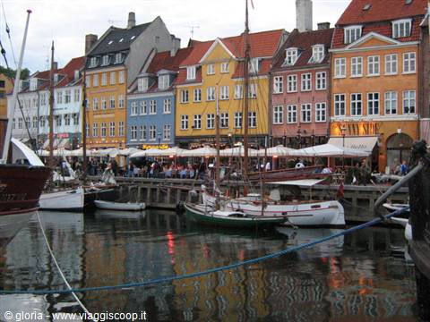 Boats moored at Nyhavn harbor, colorful townhouses and crowded cafés in Copenhagen
