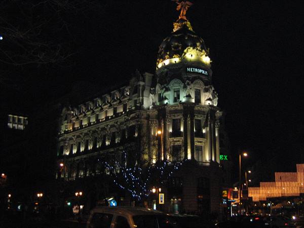 Metrópolis Building lit up at night in Madrid, golden dome and angel