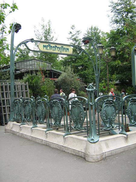 Art Nouveau green wrought-iron Metropolitain metro entrance, people passing by