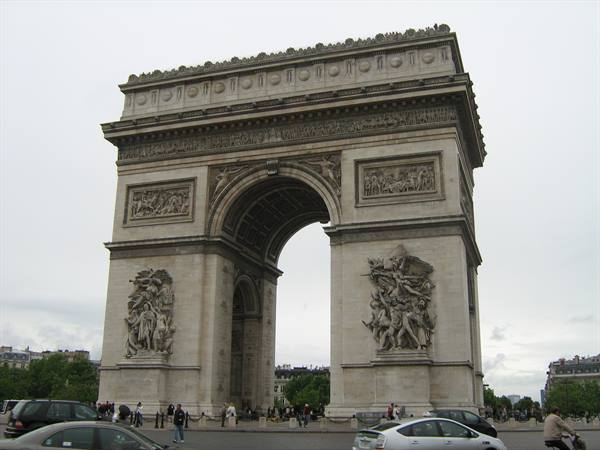 Arc de Triomphe in Paris, stone sculptures, traffic and pedestrians under gray sky