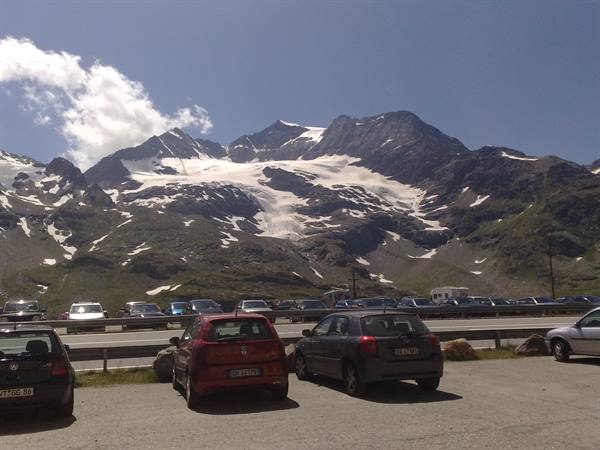 parked cars along the road in front of snowy mountains with glacier