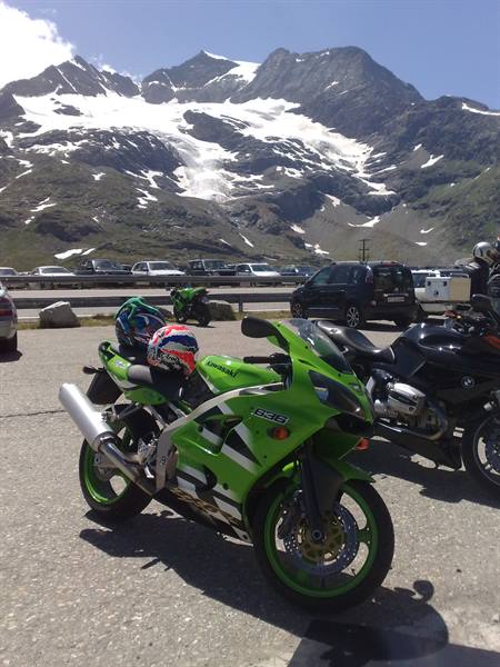 Green Kawasaki parked next to BMW bikes, snowy glacier in the background