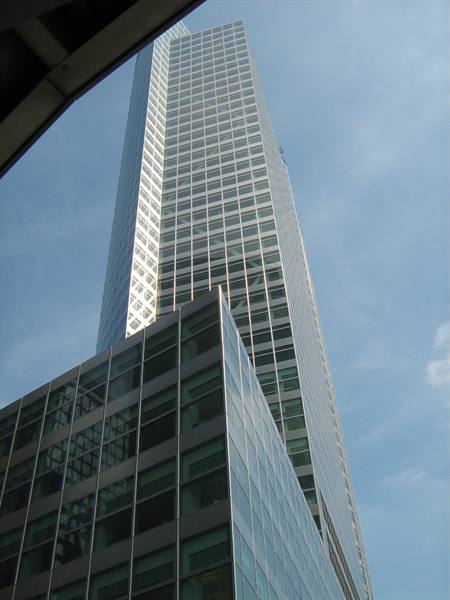 Glass skyscraper seen from below, grid facade under a blue sky