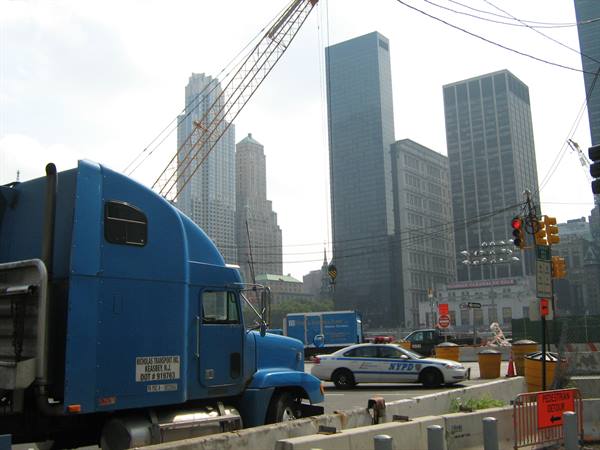Blue truck and NYPD police car at a construction site among Manhattan skyscrapers