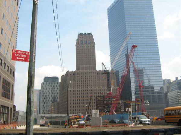 Construction site with red cranes among skyscrapers, no stopping sign, yellow bus
