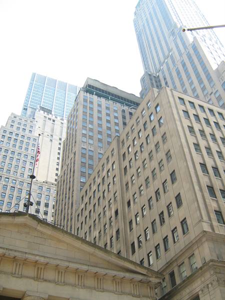 Stone skyscrapers rising above a classical pediment building, Wall Street