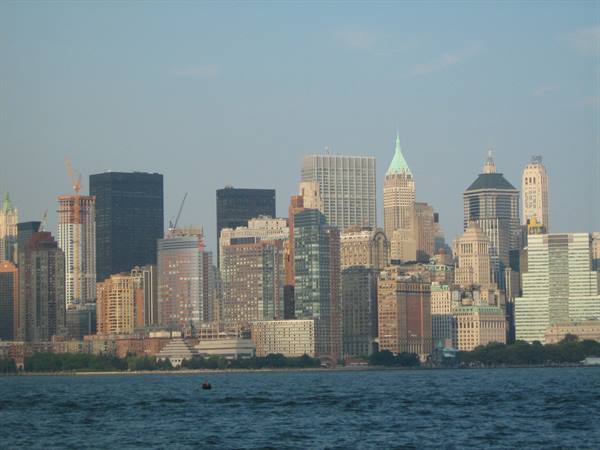 Manhattan skyscrapers across the bay, dark water in foreground, daylight
