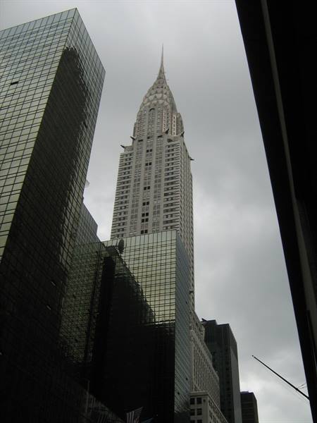 The Chrysler Building skyscraper rising between glass towers under a gray sky, New York