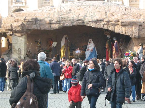 Visitors admire a large nativity scene with statues in a square