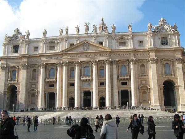 Tourists in front of the travertine facade of St. Peter's Basilica