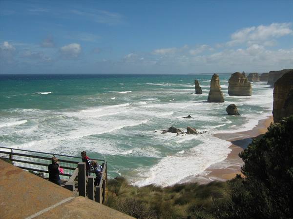 Tourists on wooden boardwalk facing the Twelve Apostles, limestone stacks in the ocean