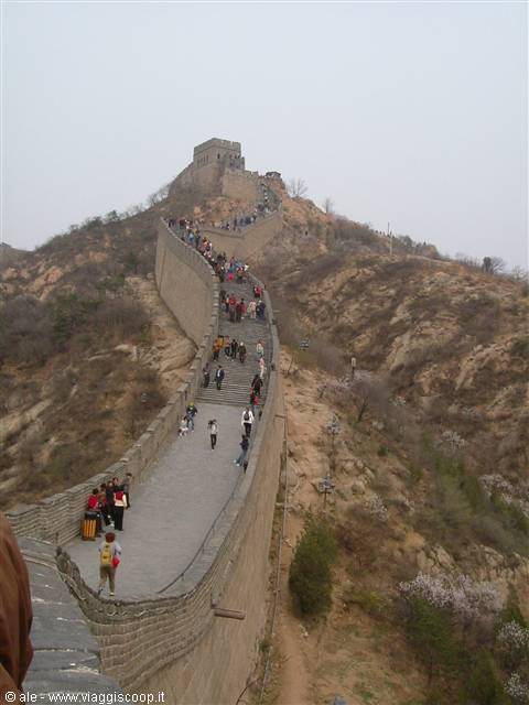 Tourists climb the stone Great Wall of China among hills