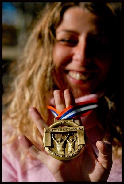 Smiling woman shows her gold 2007 New York City Marathon medal