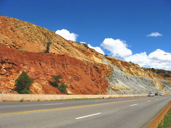 Autostrada tra banchi di roccia rossa e ocra, cielo azzurro