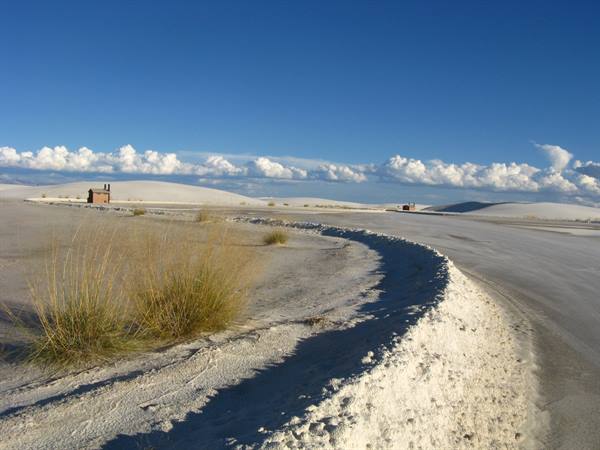 White Sands: dune di gesso bianco, erbe rade, vecchio edificio sotto nuvole