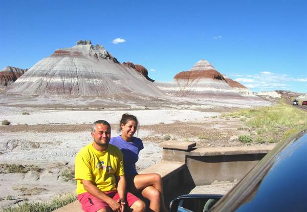 Coppia seduta su un muretto davanti alle colline striate della Painted Desert