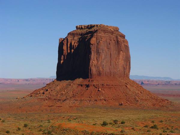 Monument Valley: maestosa butte rossastra sotto un cielo azzurro limpido