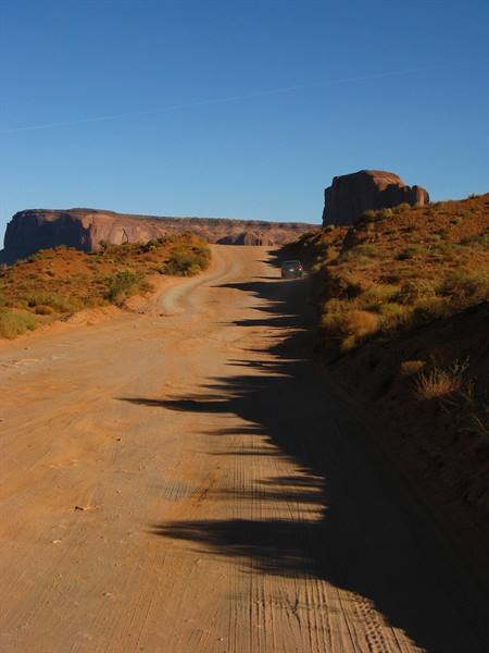 Auto sulla strada sterrata tra le formazioni rocciose di Monument Valley