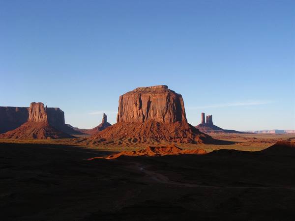 Monument Valley: imponenti butte di arenaria rossa sotto cielo azzurro