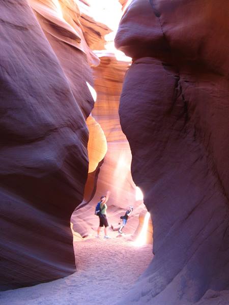 Turisti salutano tra le pareti di arenaria di Antelope Canyon