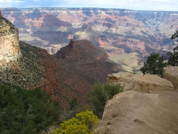 Grand Canyon: strati rocciosi rossi e ocre sotto nuvole illuminate