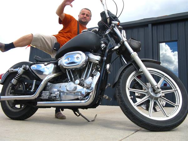 Yo: saltando accanto a una Harley Davidson nera cromata parcheggiata