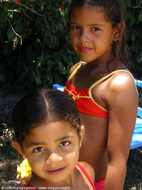 Two young girls in red swimsuits in the sunny garden greenery