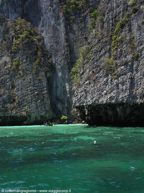Long-tail boat beneath green limestone cliffs of Ko Phi Phi
