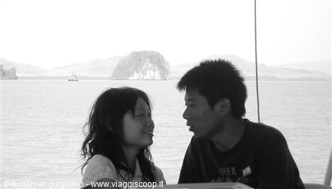 Young smiling couple on a boat, limestone islands and sea in the background