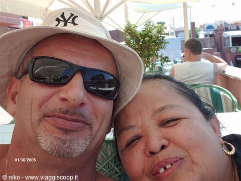 smiling couple under parasol, he wears bucket hat and sunglasses