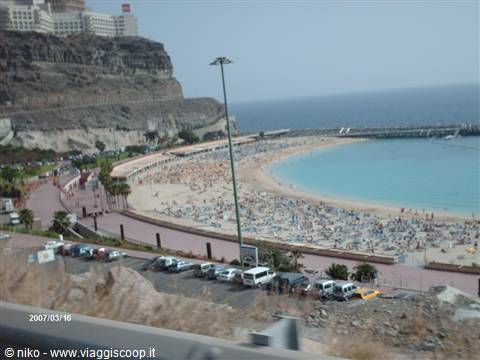 Amadores beach: pale sand, sun umbrellas, rocky cliff with hotel above