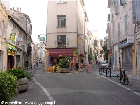 Narrow street with old buildings, colorful shop signs and parked bicycle in Arles